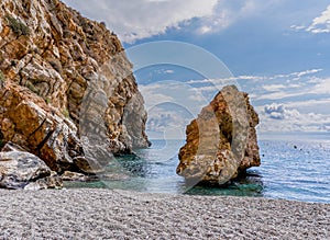 Secluded rocky beach with clear turquoise water and brown sandstone cliffs