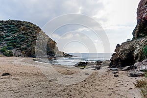 Secluded sandy beach on a wild mountainous coastline with rocks