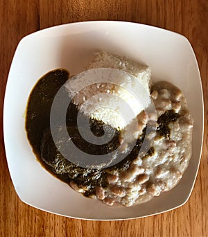 Seco de Carne, Combinado. Peruvian Recipe with Beef, Canario beans and rice on wooden table. Photo image