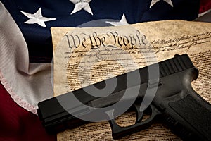 The second amendment and gun control in america concept with a handgun and the american constitution on the USA flag with close up