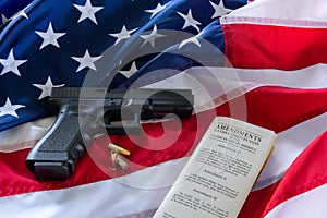 The second amendment and gun control in the US, concept. Handgun, bullets, and the american constitution on the USA flag