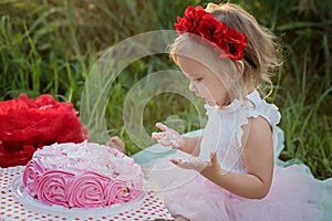 second birthday of little girl. Two years old girl sitting near celebration decorations and eating her birthday cake. Cake Smash