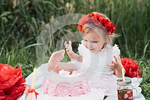 second birthday of little girl. Two years old girl sitting near celebration decorations and eating her birthday cake. Cake Smash