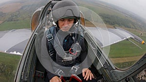 Second pilot in helmet tired and sleeping in aircraft. Gray blue combat fighter plane flying against the cloudy overcast sky