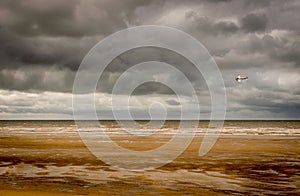 A second world war plane flying through storm clouds on the beach