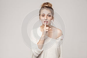 Secrecy sign. Blone woman with big eyes, showing secret shh sign