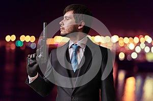 Secret agent or assassin is holding gun with silencer in hand at night photo