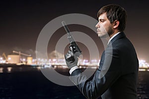 Secret agent holds pistol with silencer in hand at night