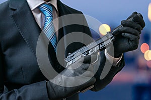 Secret agent holds pistol with silencer in hands at twilight photo