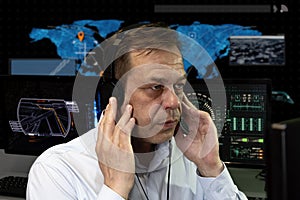 A secret agent wearing headphones watches the monitors and monitors in the military center. Concept: human surveillance, governmen