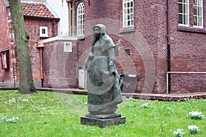 Secret garden of the beghine of amsterdam. statue in the middle of the green in the reserved and silent neighborhood inhabited by