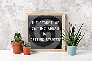 The Secret Of Getting Ahead Is Getting Started. Motivational quote on letter board, cactus, succulent flower on white table.