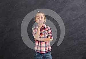 Secret. Little girl put finger on lips, hush sign