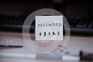 Secret password written on paper note on  keyboard with wooden desk on background. Login access, encryption and cyber security con