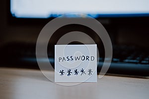 Secret password written on paper note on  keyboard with wooden desk on background. Login access, encryption and cyber security con