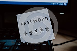 Secret password written on paper note on  keyboard with wooden desk on background. Login access, encryption and cyber security con