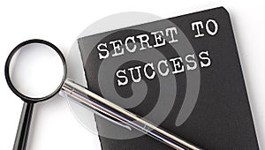 SECRET TO SUCCESS - business concept, magnifier with white text message on the black notebook