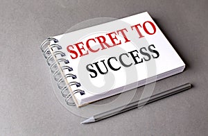 SECRET TO SUCCESS word on notebook on grey background