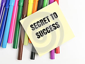 SECRET TO SUCCESS written on yellow paper note with colorful pen.