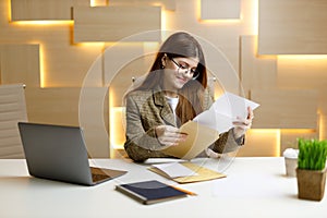 The secretary looks through the mail with documents, the woman manager checks the accounts