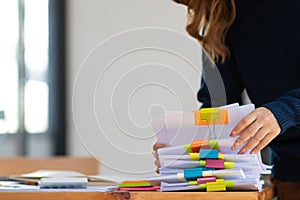 secretary searches through stacked documents on desk in office to find lease within stacked documents just before meeting. concept