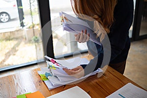 secretary searches through stacked documents on desk in office to find lease within stacked documents just before meeting. concept