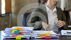 secretary searches through stacked documents on desk in office to find lease within stacked documents just before meeting. concept