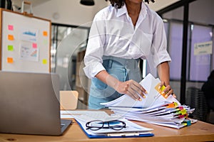 secretary searches through stacked documents on desk in office to find lease within stacked documents just before meeting. concept