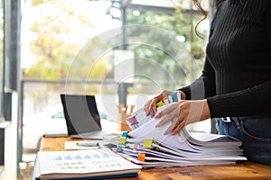 secretary searches through stacked documents on desk in office to find lease within stacked documents just before meeting. concept