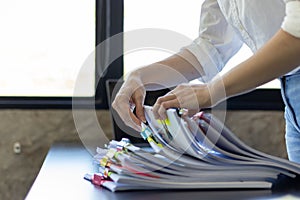 secretary searches through stacked documents on desk in office to find lease within stacked documents just before meeting. concept