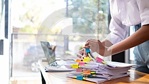 secretary searches through stacked documents on desk in office to find lease within stacked documents just before meeting. concept