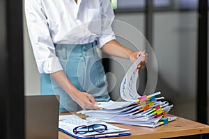 secretary searches through stacked documents on desk in office to find lease within stacked documents just before meeting. concept