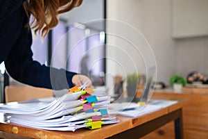 secretary searches through stacked paperwork on desk in office to find lease within stacked paperwork just before meeting. concept