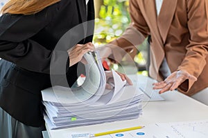 secretary searches through stacked paperwork on desk in office to find lease within stacked paperwork just before meeting. concept