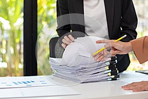 secretary searches through stacked paperwork on desk in office to find lease within stacked paperwork just before meeting. concept