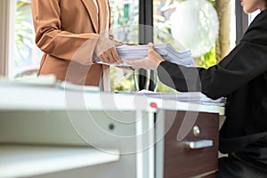 secretary searches through stacked paperwork on desk in office to find lease within stacked paperwork just before meeting. concept