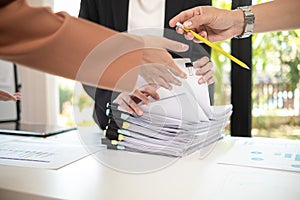 secretary searches through stacked paperwork on desk in office to find lease within stacked paperwork just before meeting. concept