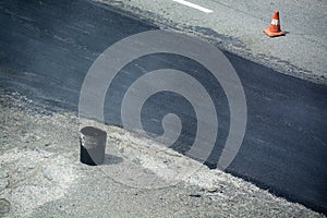 Section of road covered by the fresh asphalt.