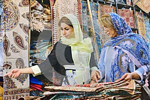 Secular Iranian women choose goods for purchase in carpet store.