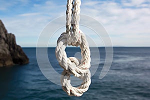 secure bowline knot on a white rope with ocean backdrop