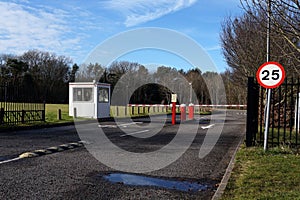 Security barrier, speed limit sign and guard hut at entrance to office parking lot