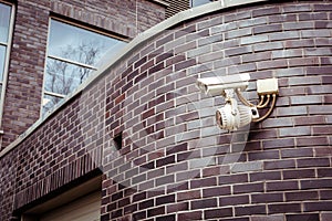Security camera on the brick wall of building.