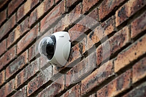 Security camera on brick wall facade