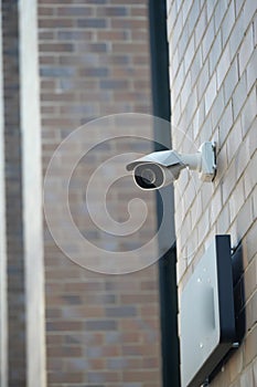 Security camera mounted on a brick wall beside an entrance