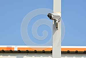 The security camera is on the pole above the roof of the house photo