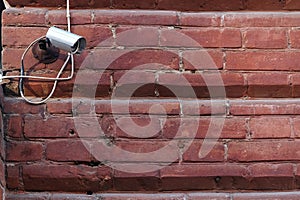 Security camera on a red brick wall.