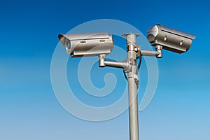 Security CCTV video camera against blue sky.