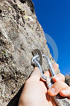 Security concept: climber inserts a quick-draw in anchor on rock