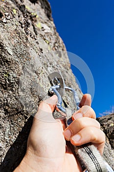 Security concept: climber inserts a quick-draw in anchor on rock