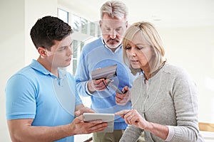 Security Consultant Demonstrating Alarm System To Mature Couple